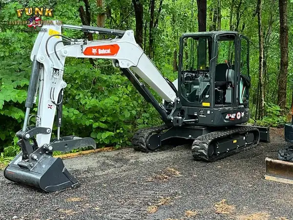 Compact excavator handling site preparation for a landscape installation in Worcester County, MA by Funk Landscape & Design