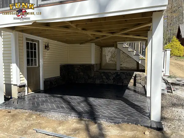 Covered paver patio with natural stone knee wall, built by Funk Landscape & Design