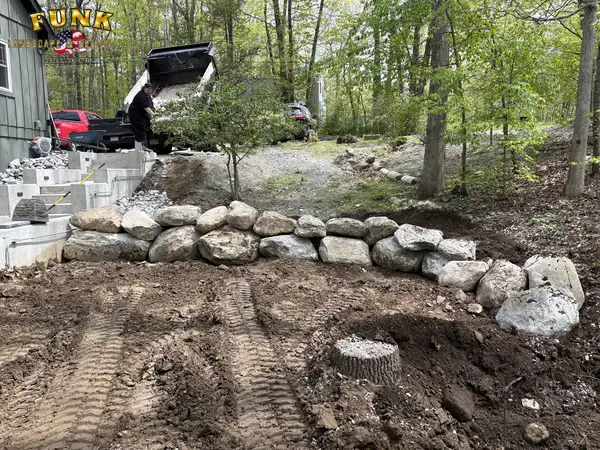 Excavated ground with boulders staged at the start of a lakeside patio project