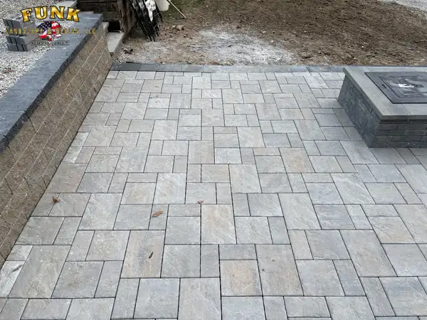 Finished large-format paver patio with fire pit and retaining wall by Funk Landscape & Design