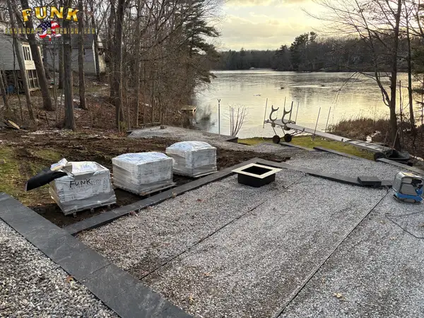 Pallets of wall block staged on the patio base beside the lake