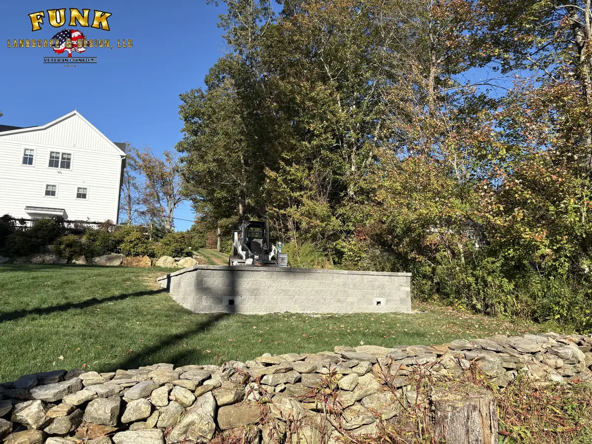 Low stone retaining wall bordering a back lawn