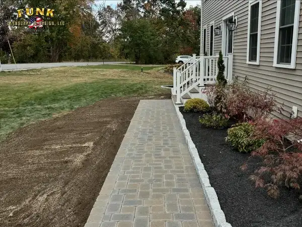 Finished paver walkway beside planting beds and fresh lawn