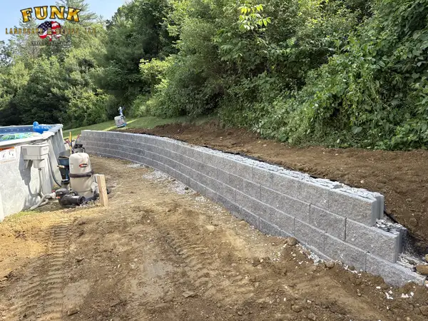 Long block retaining wall with fresh gravel backfill beside the pool