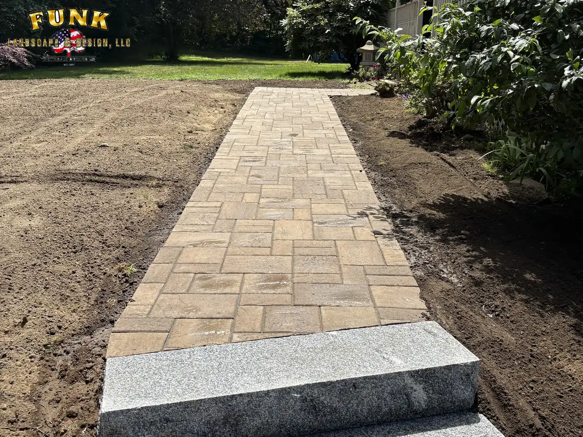 Tan paver walkway with granite edge through the graded yard