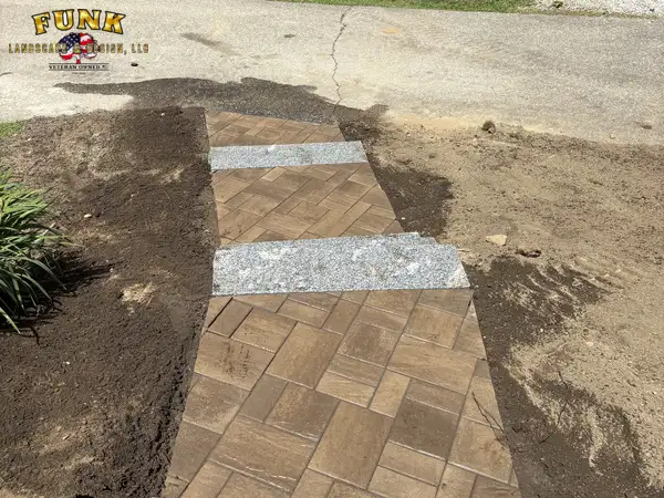Herringbone paver walkway with granite accent bands, soil graded alongside