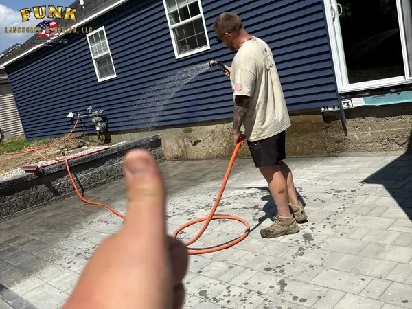 Thumbs up as a crew member washes down the freshly laid paver patio