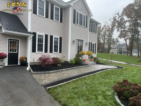 Full front-yard landscape installation with paver walkway, mulched planting beds, and new lawn in Worcester County, MA by Funk Landscape & Design