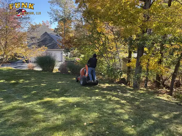 Crew mowing a lawn beneath fall foliage
