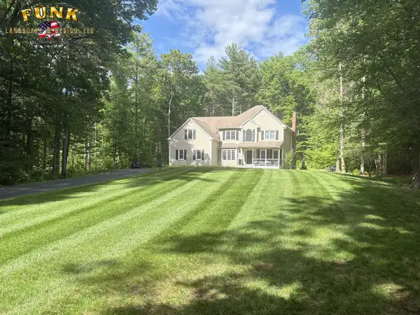 Wide healthy lawn with fresh mowing stripes framing a colonial home