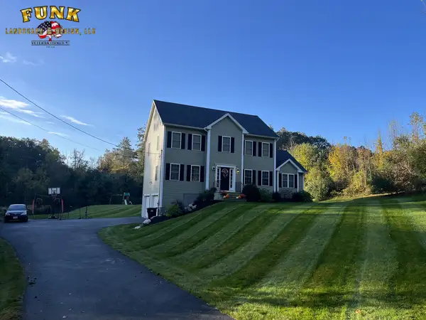 Golden-hour mowing stripes on a front lawn beside a colonial home